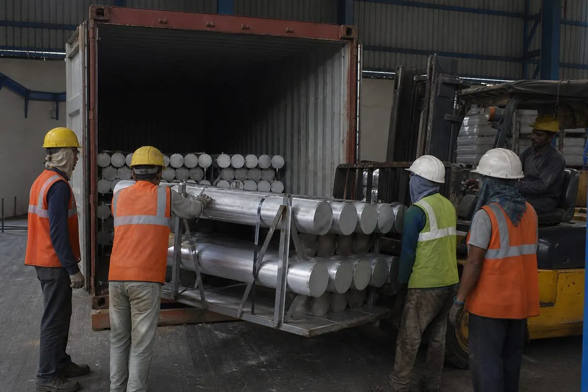 Workers stuffing aluminium extrusion billet bundles into a shipping container for FCL export from India