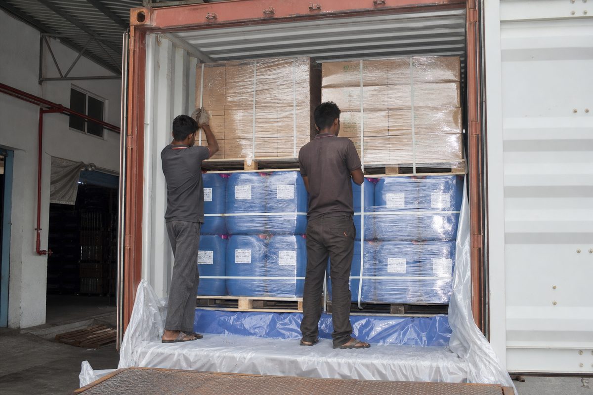 Workers stuffing palletized Ayurvedic massage oil drums into a shipping container for leak-protected FCL export from India