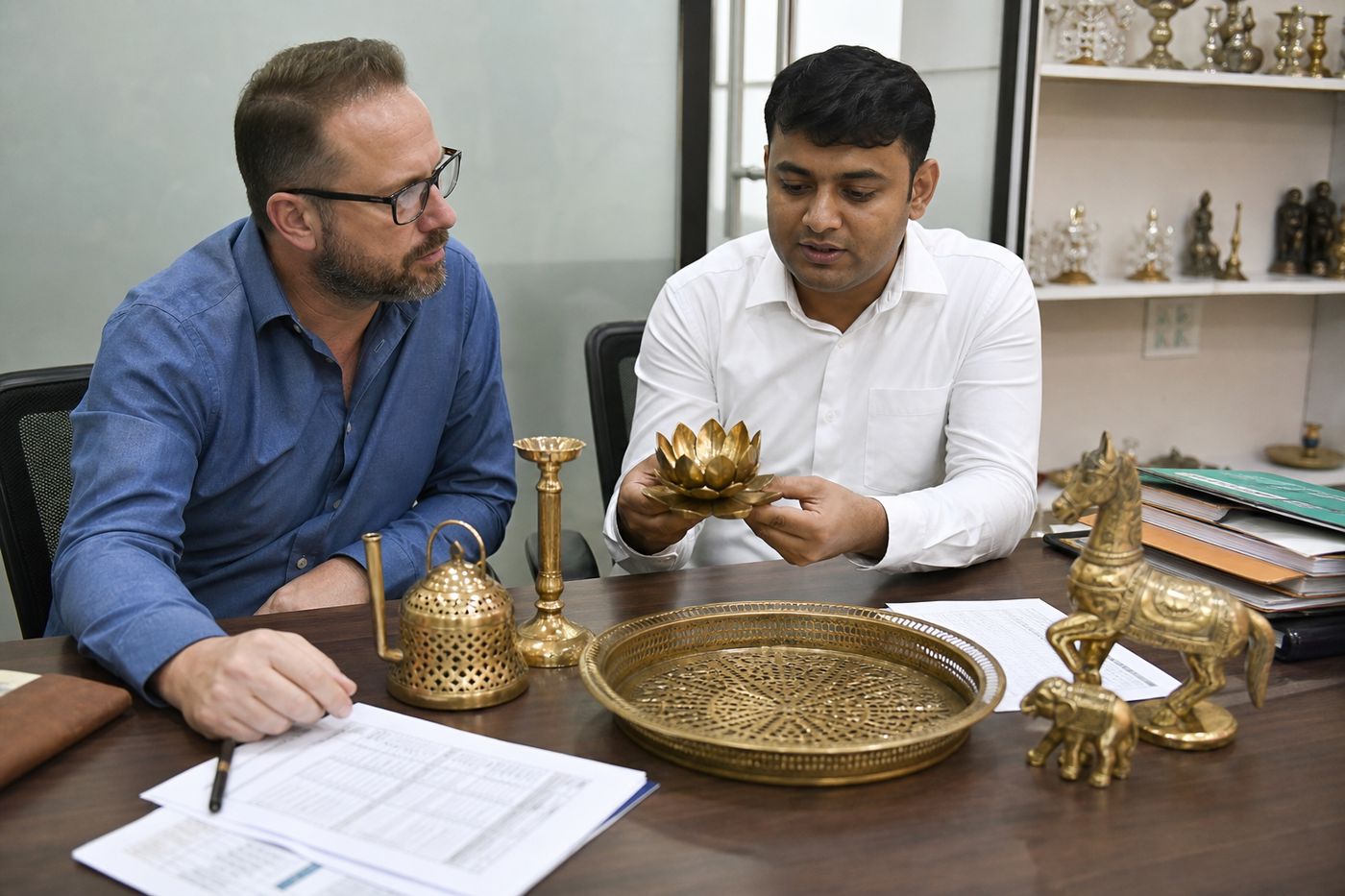 International buyer reviewing Indian brass decorative samples and export documents with a sourcing partner