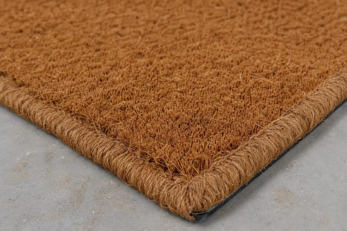 Close-up of a natural coconut coir doormat showing dense fibre pile and bound edge for export