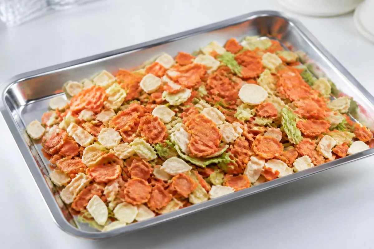 Export-grade dehydrated carrot flakes and mixed dried vegetables in a stainless steel sample tray from India