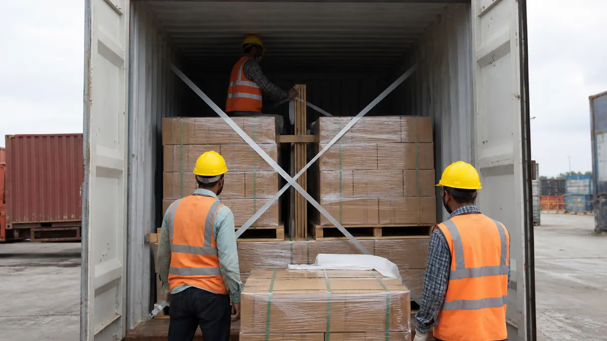 Workers stuffing palletized fastener cartons into a shipping container for FCL export from India