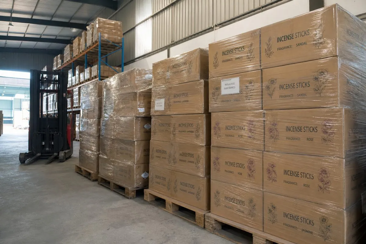Palletized stretch-wrapped incense stick cartons staged in a dry Indian export warehouse
