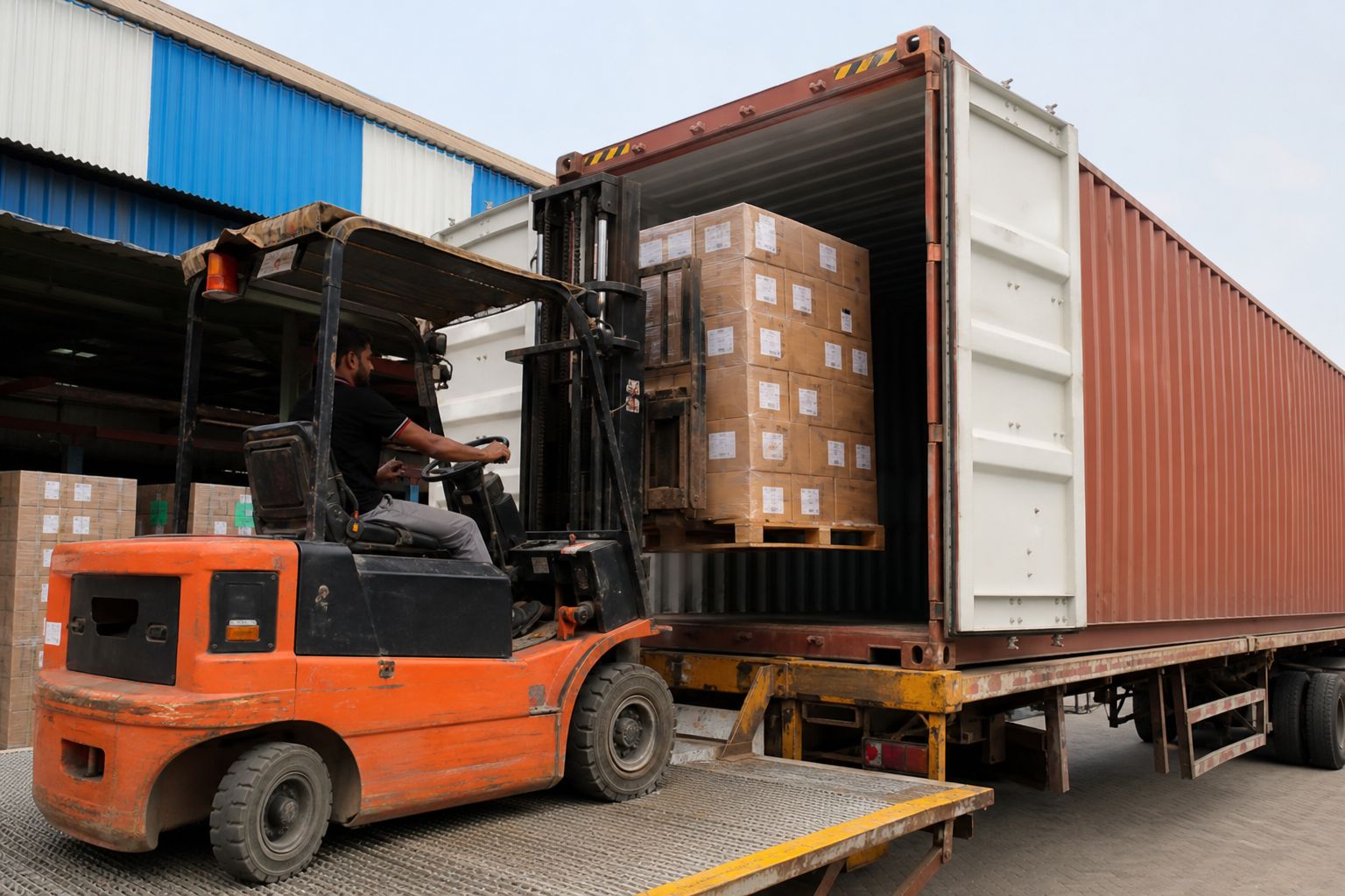 Forklift loading palletised master cartons of leather shoes into a shipping container at an Indian port yard
