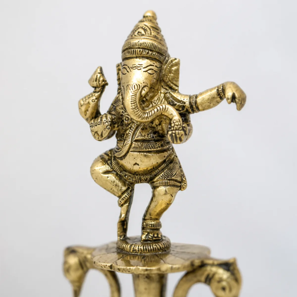 Close-up of the four-armed dancing Ganesha figurine on a brass oil lamp