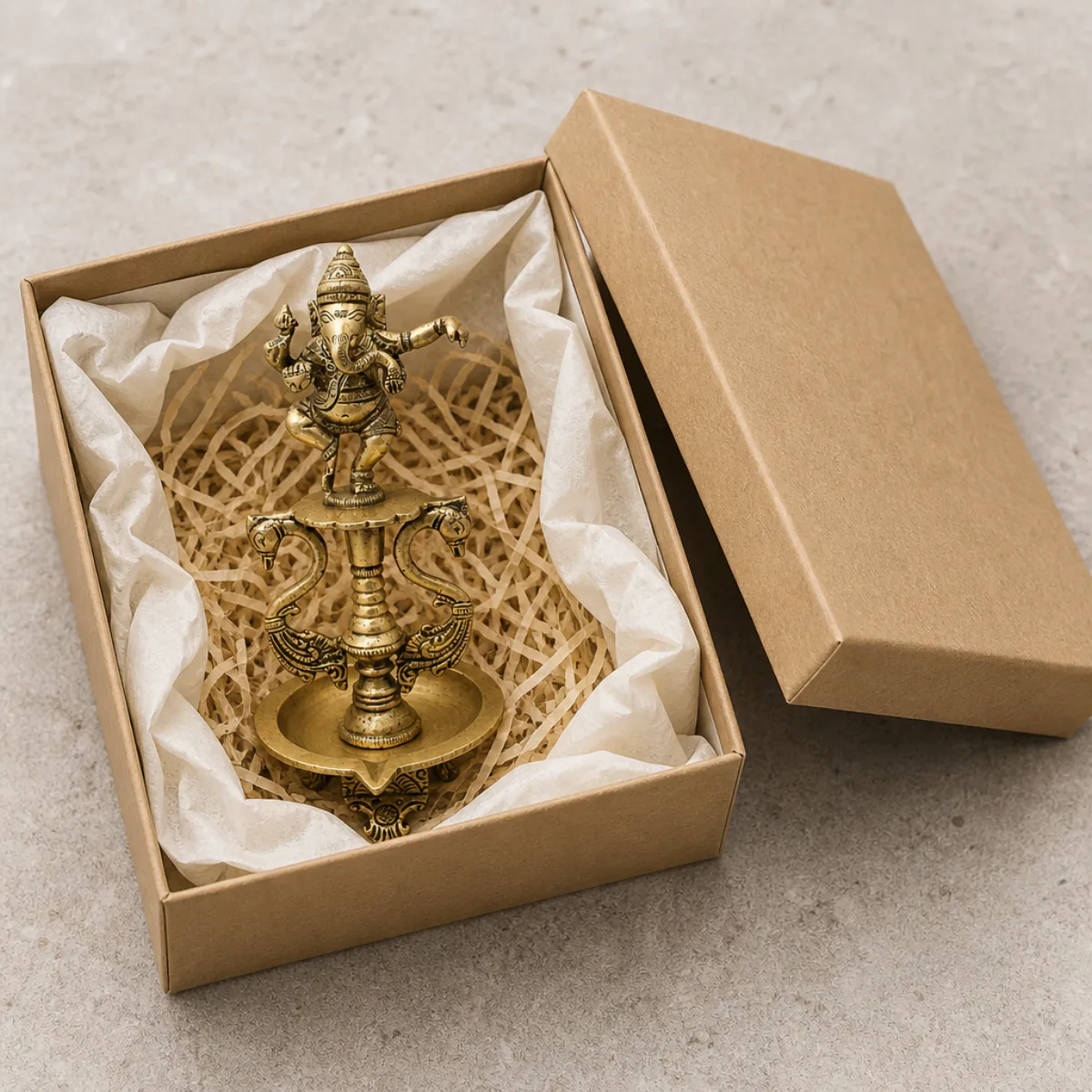 Brass dancing Ganesha diya packed in a kraft gift box with tissue for export