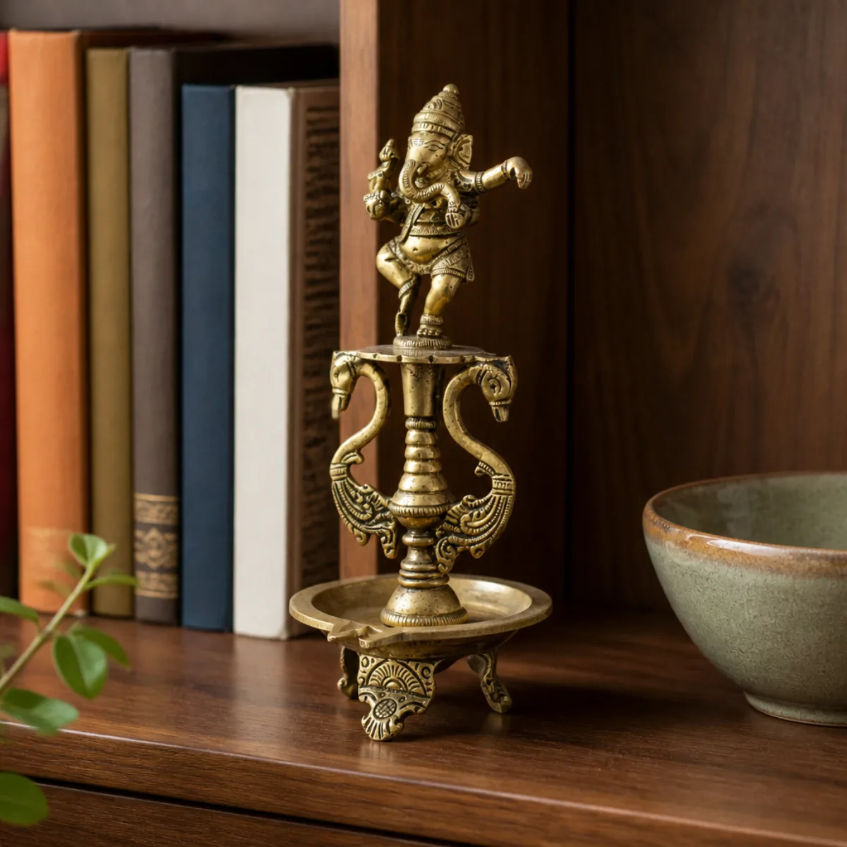 Brass dancing Ganesha diya used as bookshelf décor among books