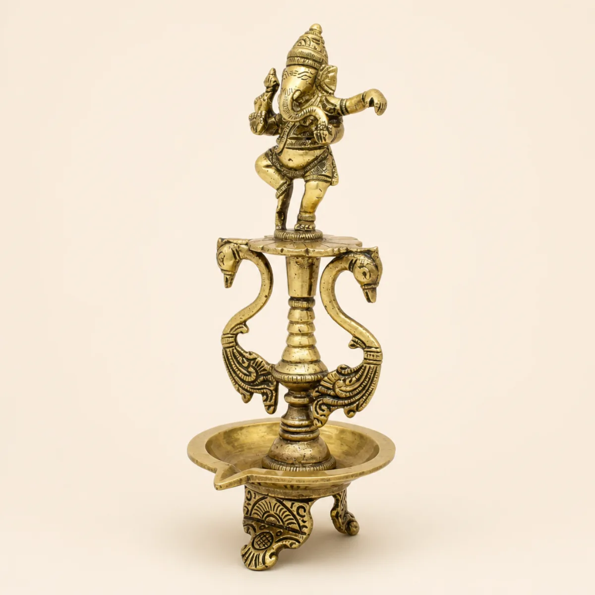 Side view of a handmade brass dancing Ganesha diya showing bowl depth and hamsa brackets