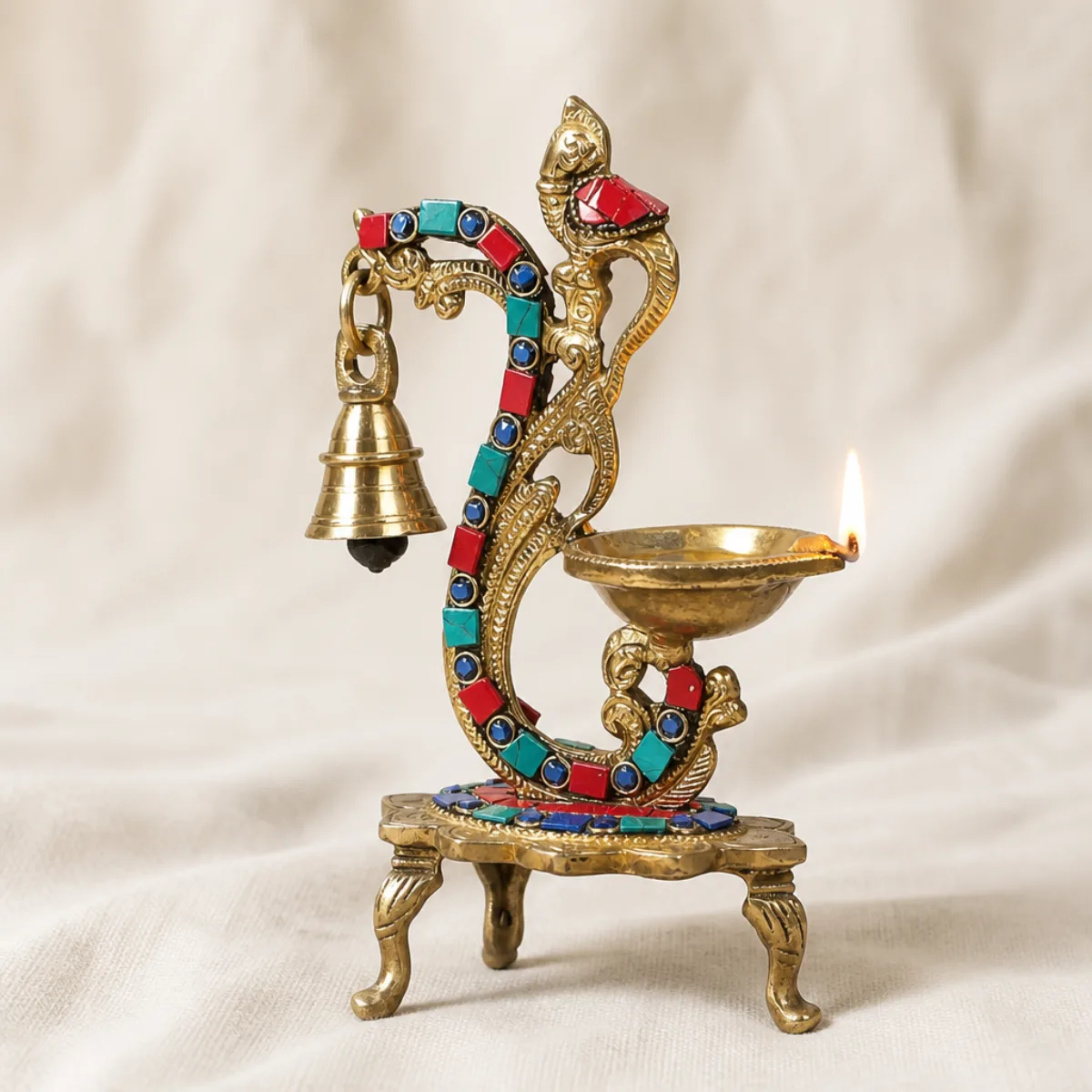 Side view of a handmade brass peacock diya with stone mosaic and hanging bell