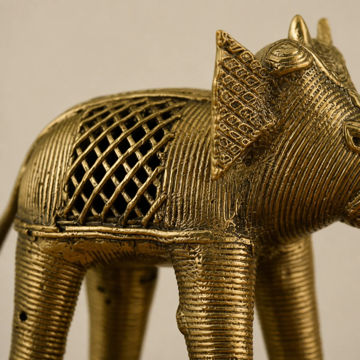 Close-up of Dhokra lost-wax coiled-wire texture and jaali lattice on a brass elephant