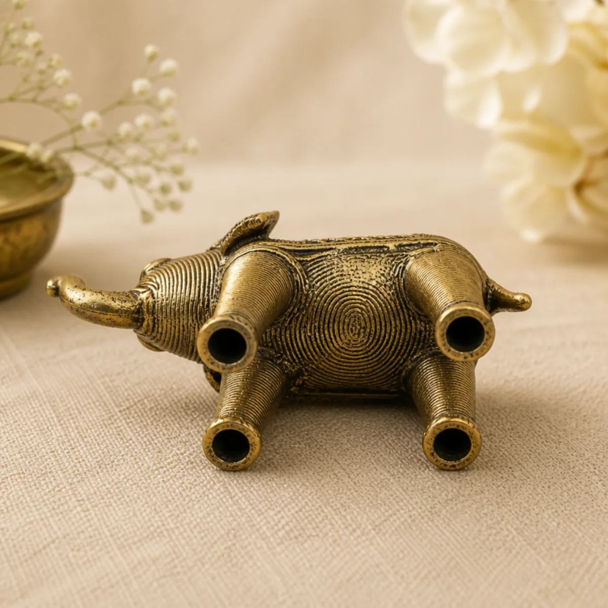 Rear view of a handmade Dhokra brass elephant showing tail, ears, and coiled-wire legs