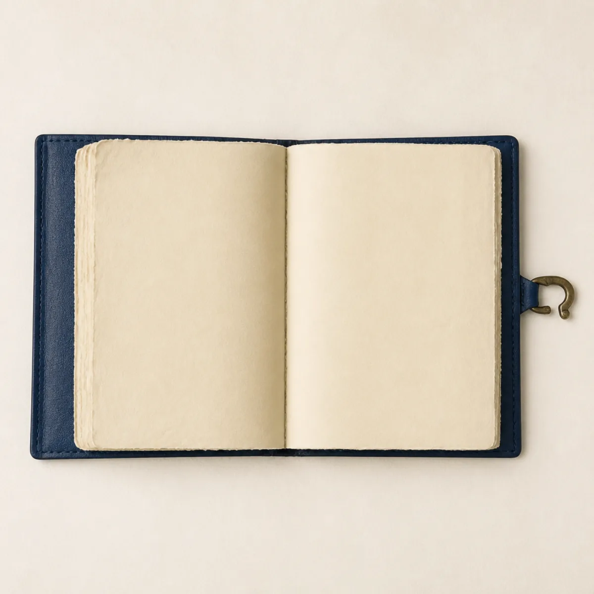 Open handmade leather journal showing unruled yellowish deckle-edge pages