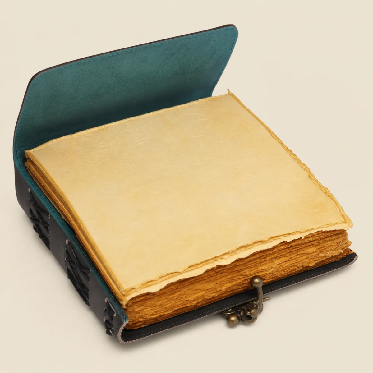 Open handmade leather journal showing unruled yellowish deckle-edge pages