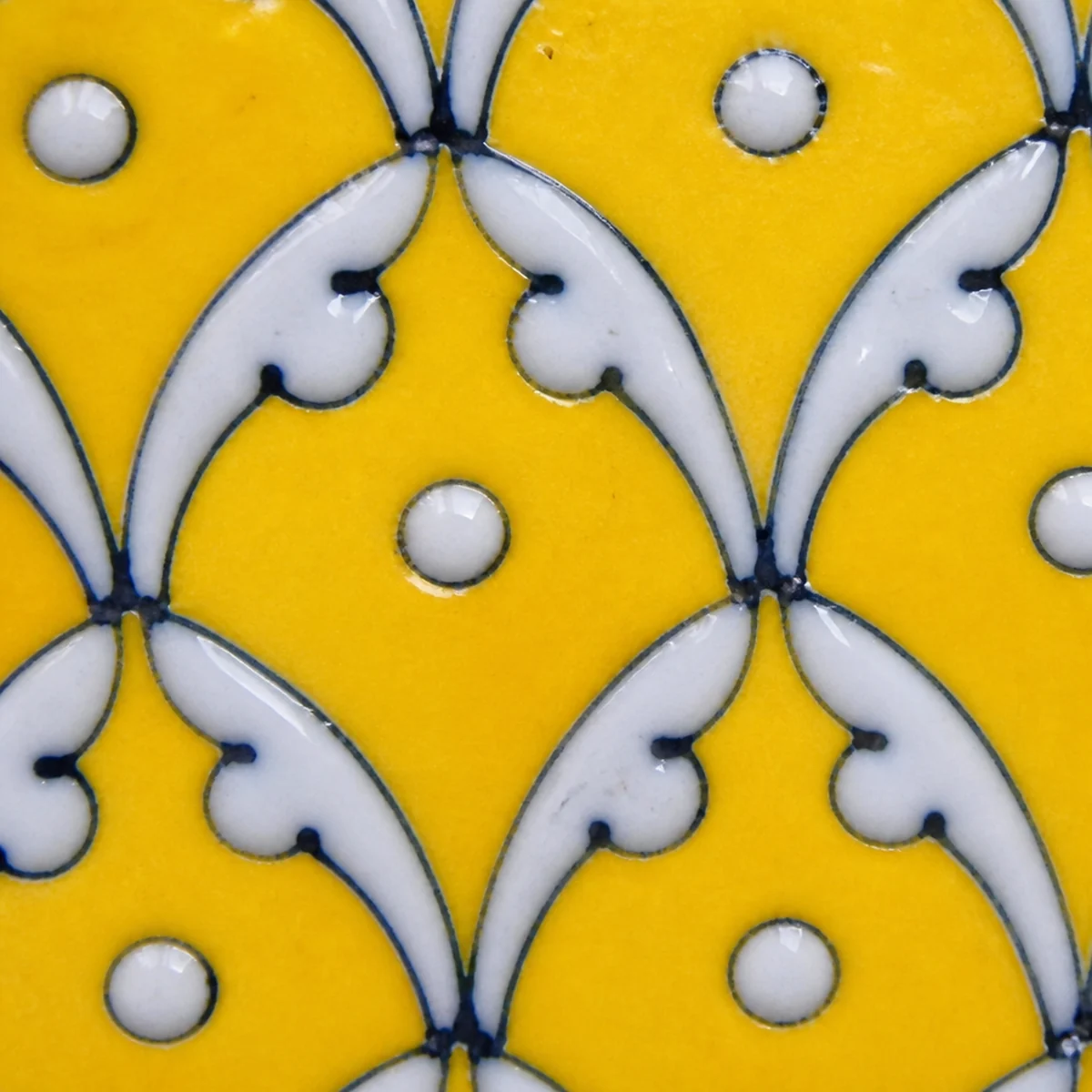 Close-up of hand-painted yellow jaal lattice on Jaipur Blue Pottery