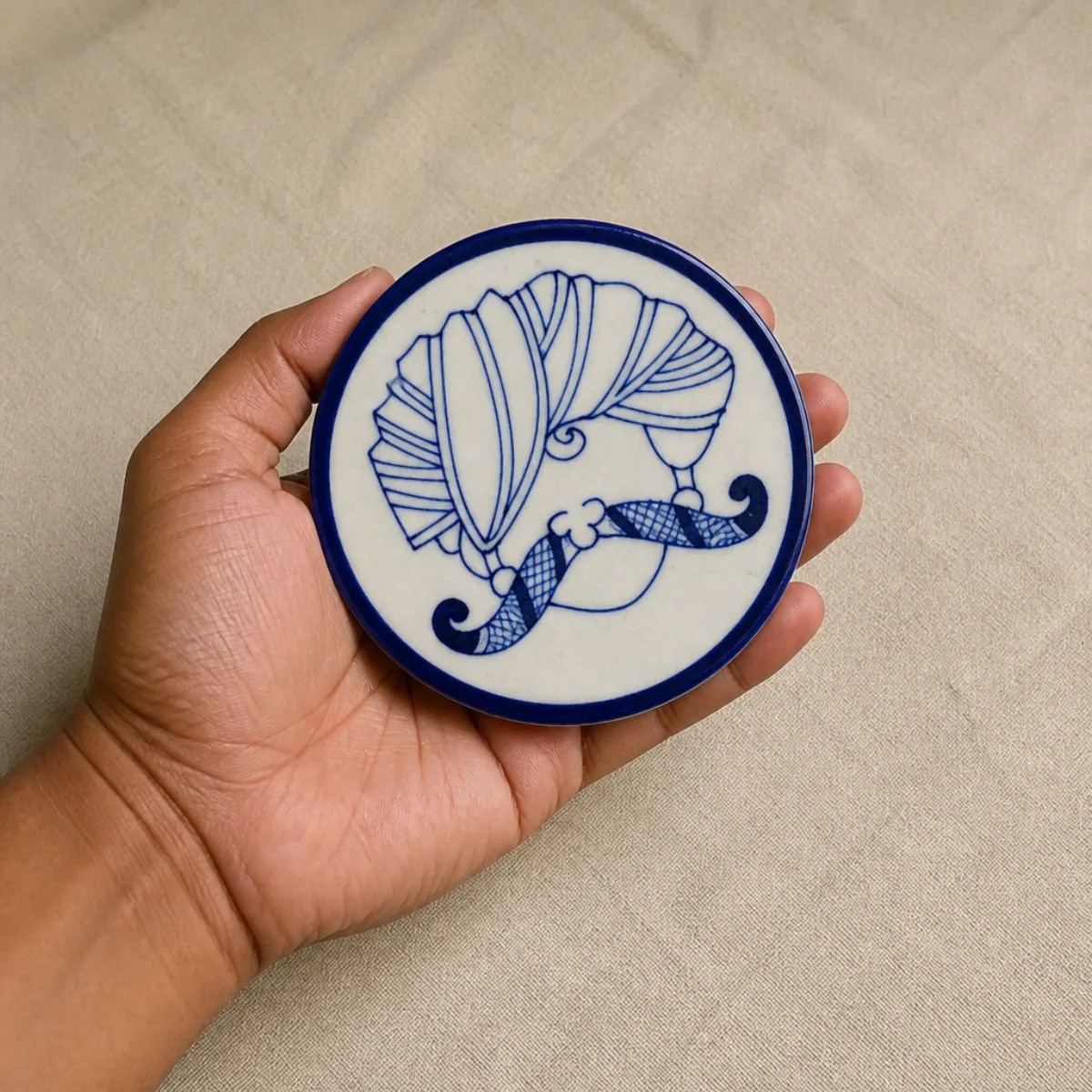 Hand holding a 4-inch Jaipur Blue Pottery coaster to show scale