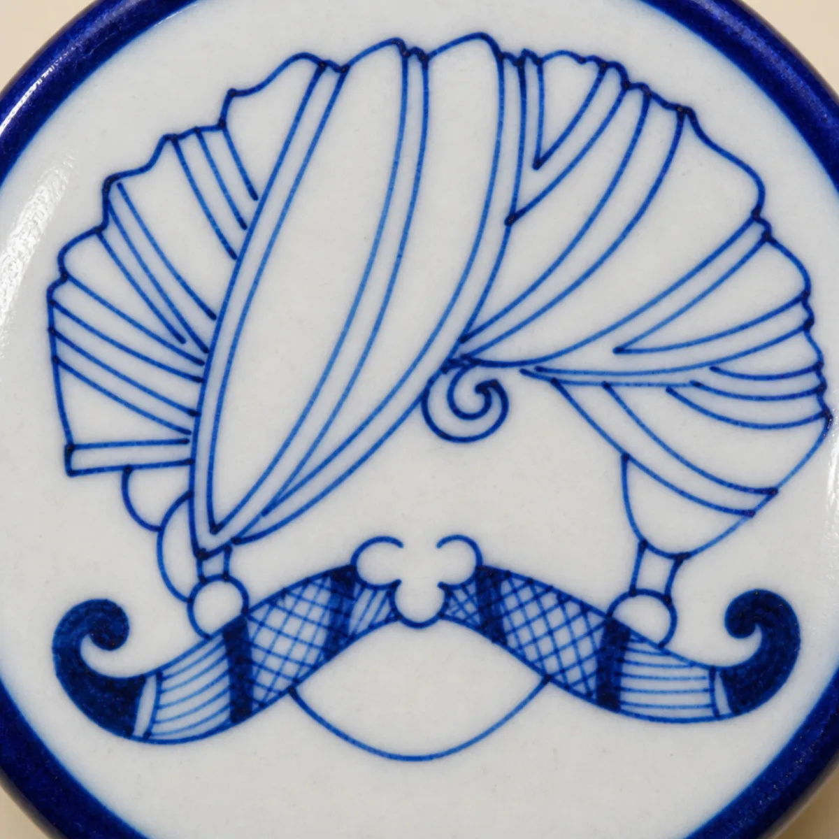 Close-up of hand-painted cobalt royal turban and checkered moustache on Jaipur Blue Pottery
