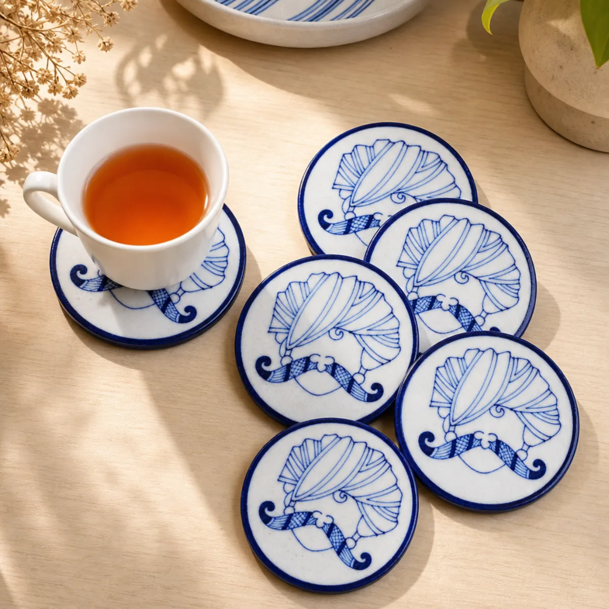 Jaipur Blue Pottery coasters used under a tea cup on a cream table
