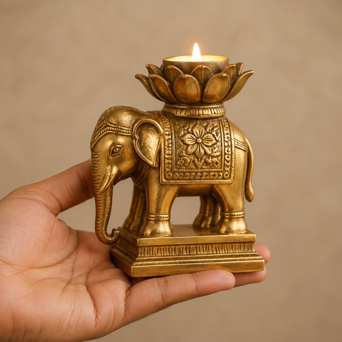 Hand holding a pure brass elephant candle holder to show 14 cm scale and solid weight