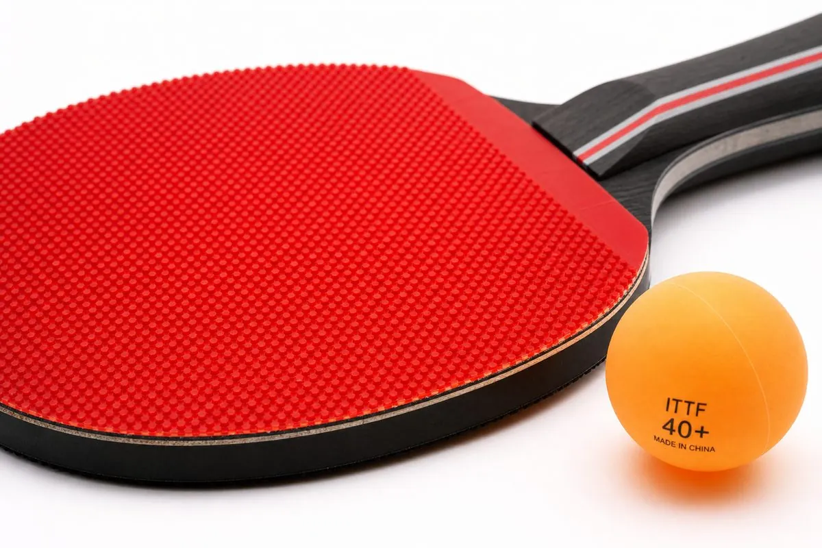Close-up of a carbon table tennis paddle and ITTF 40+ poly ball showing rubber surface and blade edge