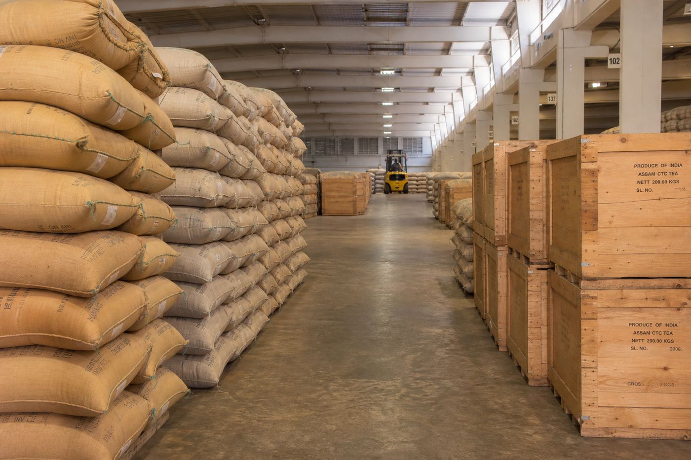 Stacked multiwall tea sacks and wooden tea chests stored in a climate-aware Indian export warehouse