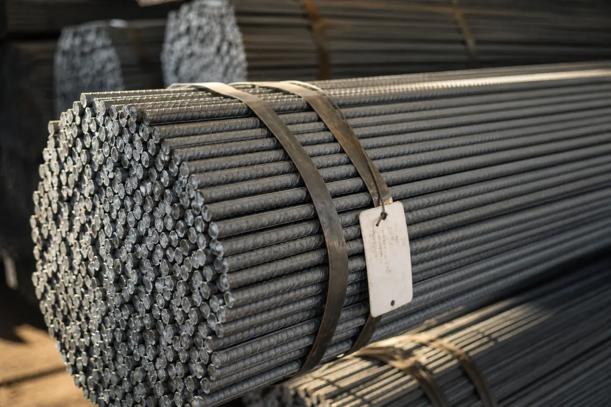 Close-up of a hexagonal TMT bar export bundle showing deformed rib pattern, steel strapping, and grade tags under BIS IS 1786